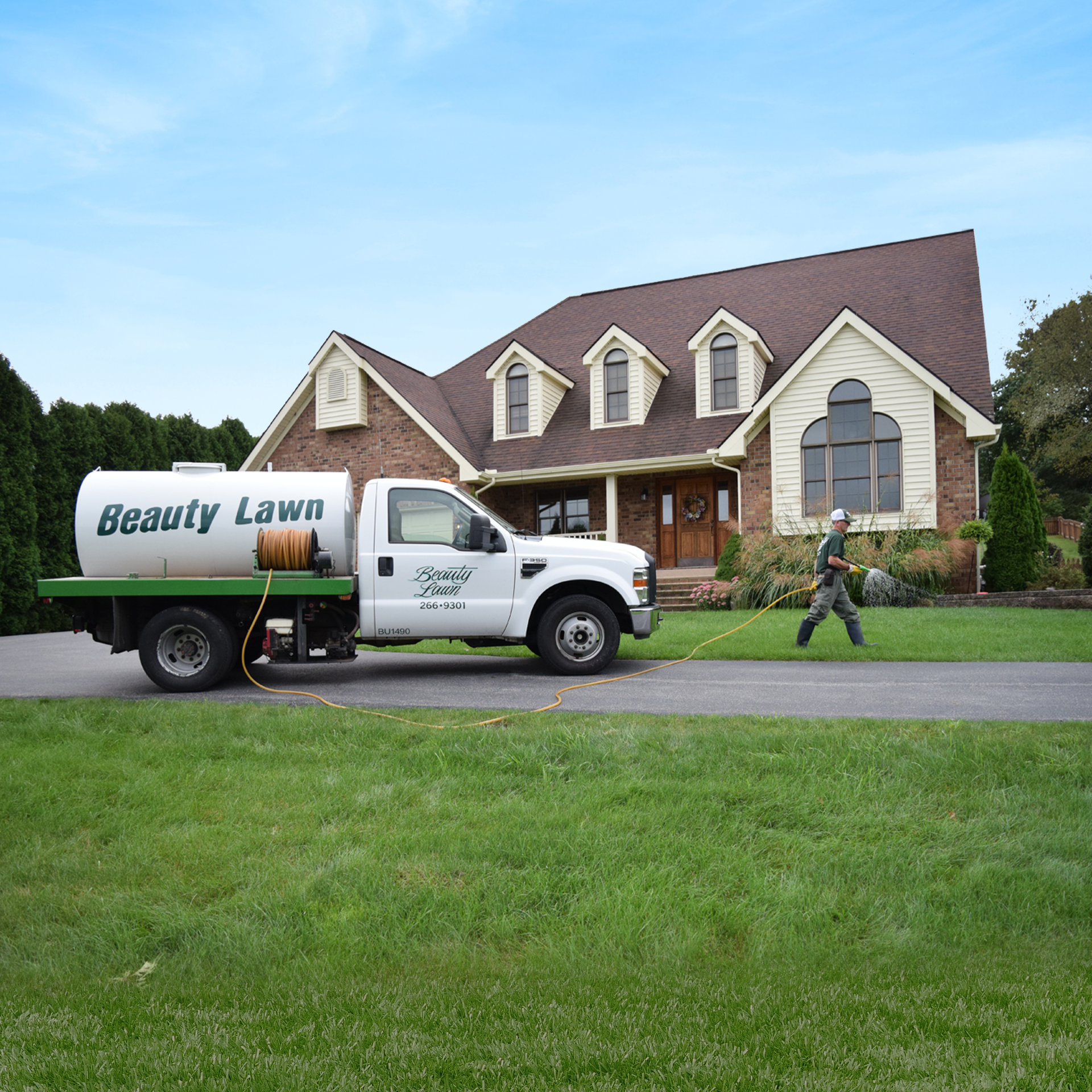 Beauty Lawn truck parked in front of house with technician performing lawn spraying service